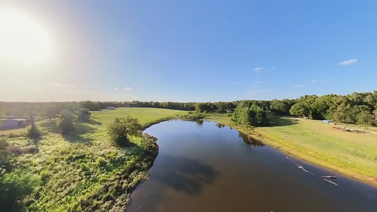 Drone view of the larger pond, a long curve with mowed pasture on one bank and woods on the other